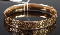 Lot 404 - A rolled gold hinge bangle with safety chain