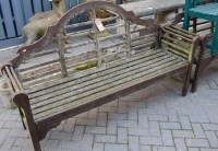Lot 1328 - A pair of stained teak slatted three seater...