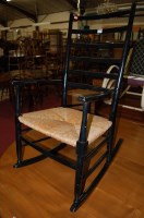 Lot 1266 - A black lacquered rocking chair, having a...