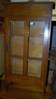 Lot 1381 - A small 1930s oak ledgeback single door glazed...