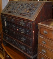 Lot 1215 - An antique heavily carved oak slopefront...