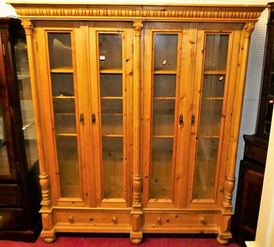 Lot 1148 - A continental pine glazed four door bookcase,...