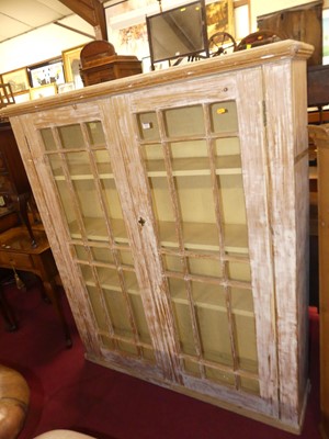Lot 1322 - A limed pine double door bookcase, having...