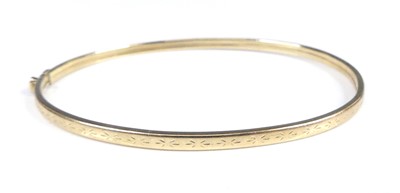 Lot 2906 - A modern 9ct gold hinged bangle, having carved...