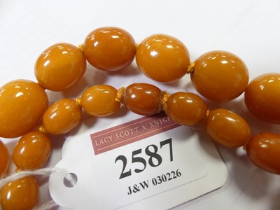 Lot 2587 - A butterscotch amber beaded necklace, arranged...