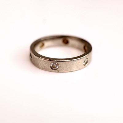Lot 119 - A platinum diamond set wedding band, featuring...